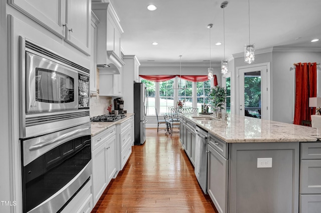 216 Colonial Ridge Dr, Pittsboro, NC 27312 - kitchen featuring stainless steel appliances, gray cabinets, a sink, wood finished floors, and an island with sink