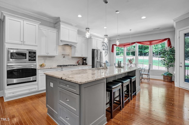 216 Colonial Ridge Dr, Pittsboro, NC 27312 - kitchen featuring appliances with stainless steel finishes, gray cabinetry, a large island with sink, hardwood / wood-style flooring, and white cabinetry