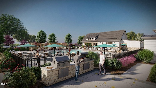 view of patio / terrace with an outdoor kitchen, fence, a swimming pool, and area for grilling