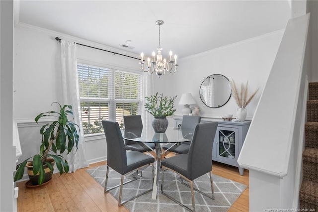 dining area with a chandelier, wood finished floors, and ornamental molding