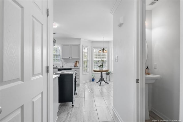 hall with baseboards, a chandelier, and light marble finish flooring