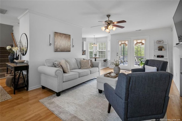 living room with a ceiling fan, light wood-style floors, a chandelier, ornamental molding, and baseboards