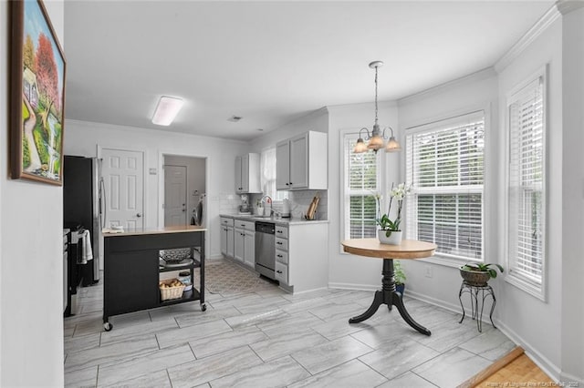 kitchen with stainless steel appliances, ornamental molding, light countertops, a sink, and a chandelier