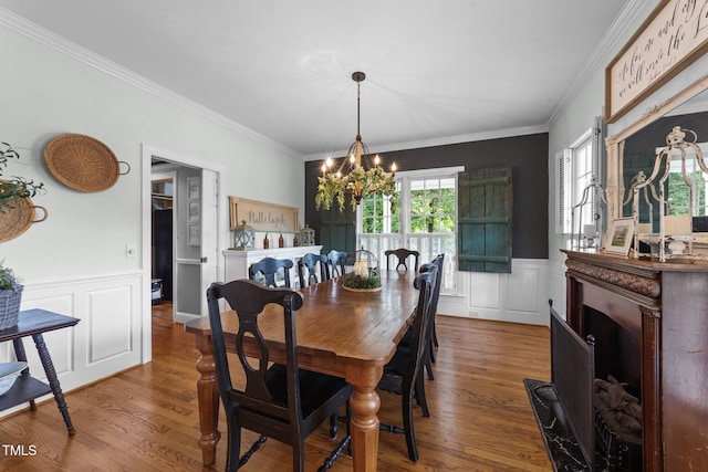 5308 Stableview Ct, Holly Springs, NC 27540 - dining space with a chandelier, ornamental molding, a decorative wall, wood finished floors, and wainscoting