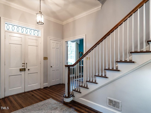 foyer featuring wood finished floors, ornamental molding, and stairway