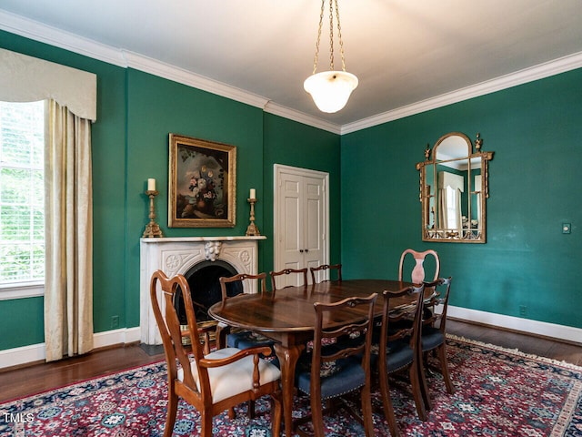 dining room featuring wood finished floors, baseboards, crown molding, and a fireplace