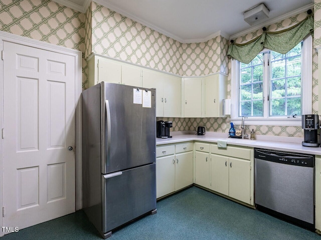 kitchen featuring appliances with stainless steel finishes, crown molding, light countertops, wallpapered walls, and a sink