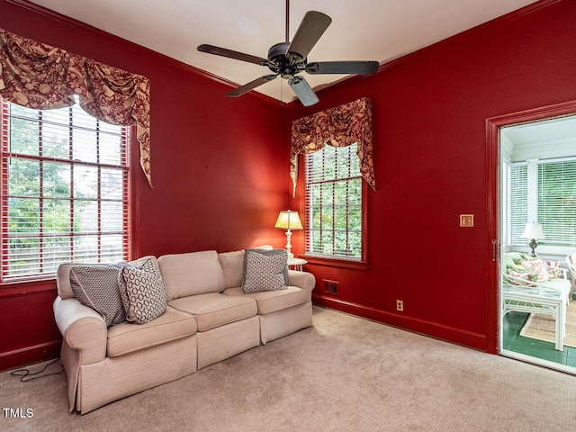 carpeted living area featuring ceiling fan, ornamental molding, and baseboards