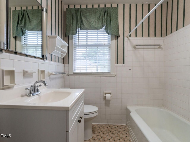 bathroom featuring plenty of natural light, a tub, wallpapered walls, toilet, and tile walls