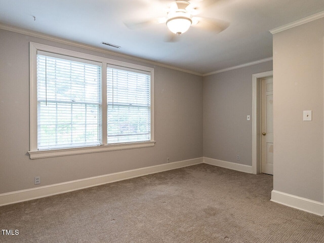 spare room featuring carpet, a ceiling fan, baseboards, and crown molding