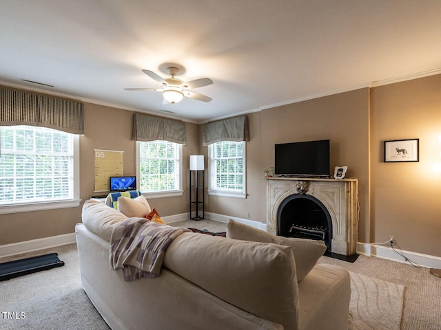 living room with baseboards, light carpet, crown molding, a ceiling fan, and a fireplace with flush hearth