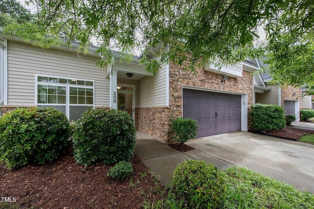 view of front facade featuring stone siding, driveway, and an attached garage