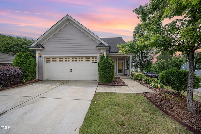 view of front of house featuring driveway, an attached garage, a front yard, and a shingled roof