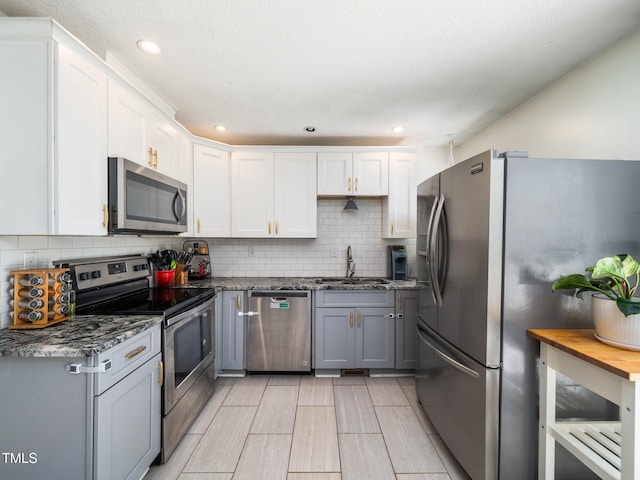 7605 Copper Mine Ln, Raleigh, NC 27615 - kitchen with appliances with stainless steel finishes, a sink, backsplash, white cabinets, and recessed lighting