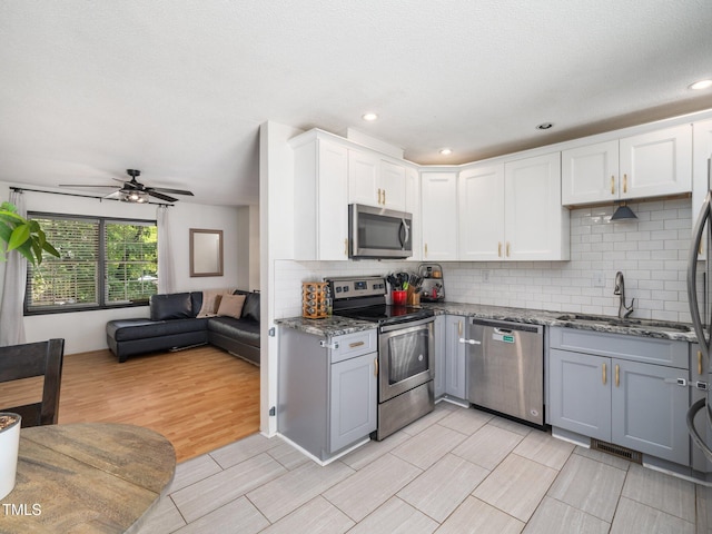 7605 Copper Mine Ln, Raleigh, NC 27615 - kitchen featuring stainless steel appliances, a sink, open floor plan, stone counters, and white cabinets
