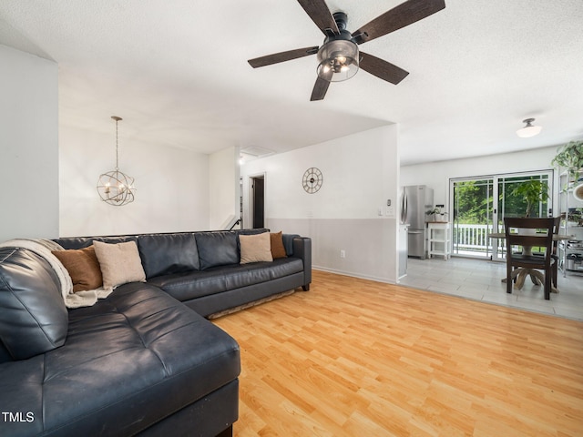 7605 Copper Mine Ln, Raleigh, NC 27615 - living room featuring wood finished floors, a textured ceiling, a ceiling fan, and a chandelier