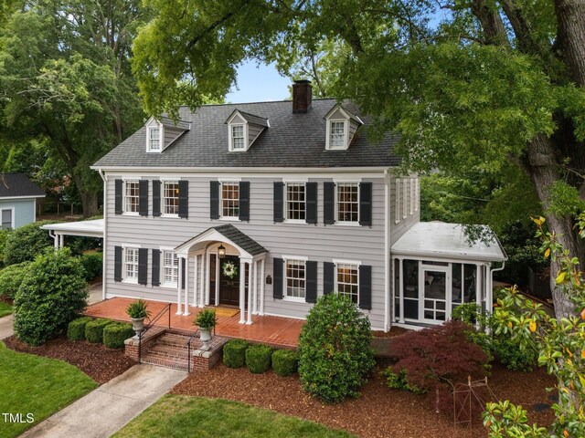 1015 Watts St, Durham, NC 27701 - colonial-style house featuring a chimney, a sunroom, and covered porch