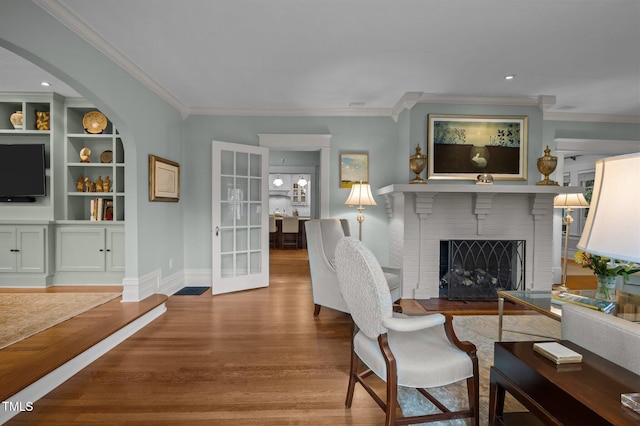 1015 Watts St, Durham, NC 27701 - living room featuring ornamental molding, wood finished floors, a brick fireplace, baseboards, and french doors