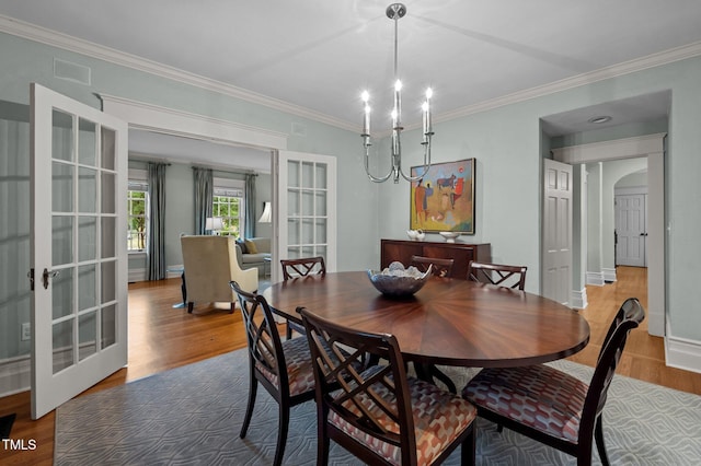 1015 Watts St, Durham, NC 27701 - dining room with wood finished floors, french doors, a chandelier, ornamental molding, and arched walkways