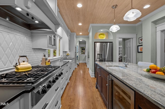 1015 Watts St, Durham, NC 27701 - kitchen featuring a sink, stainless steel appliances, premium range hood, beverage cooler, and decorative light fixtures