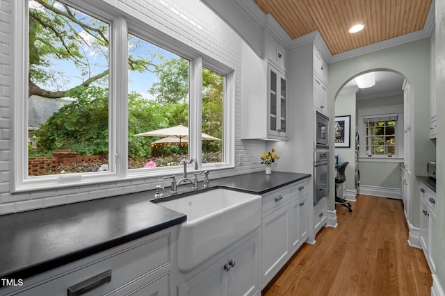 1015 Watts St, Durham, NC 27701 - kitchen featuring dark countertops, a sink, appliances with stainless steel finishes, ornamental molding, and white cabinets