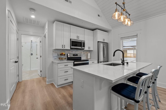 1015 Watts St, Durham, NC 27701 - kitchen with appliances with stainless steel finishes, a sink, vaulted ceiling, light wood-style flooring, and a breakfast bar