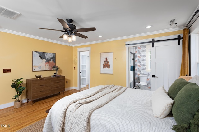 bedroom with a barn door, light wood finished floors, ornamental molding, baseboards, and recessed lighting