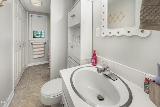 bathroom featuring baseboards, toilet, and vanity