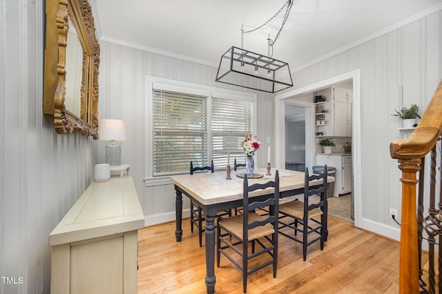 dining room featuring ornamental molding, light wood-type flooring, a chandelier, and baseboards
