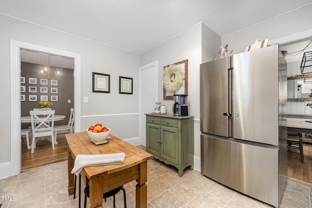 kitchen featuring green cabinets, freestanding refrigerator, baseboards, and light tile patterned flooring