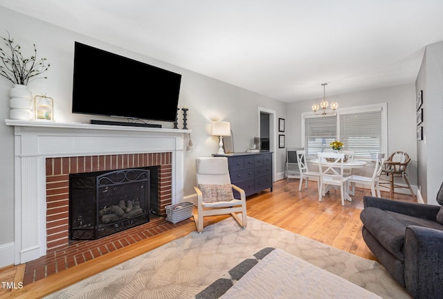 living room with a chandelier, wood finished floors, a fireplace, and baseboards