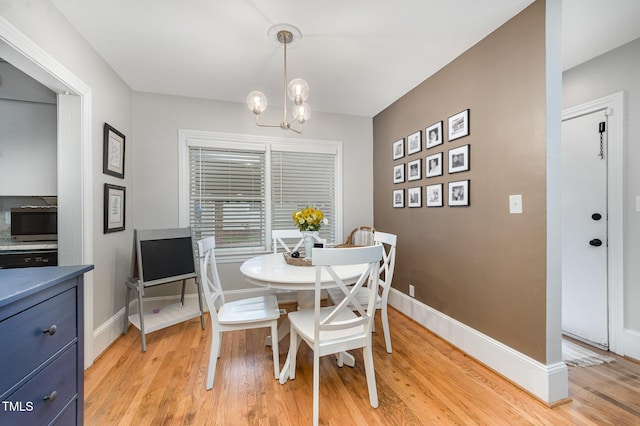 dining space featuring light wood-style floors, a chandelier, and baseboards