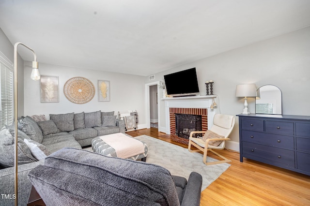 living room with light wood-style flooring and a brick fireplace