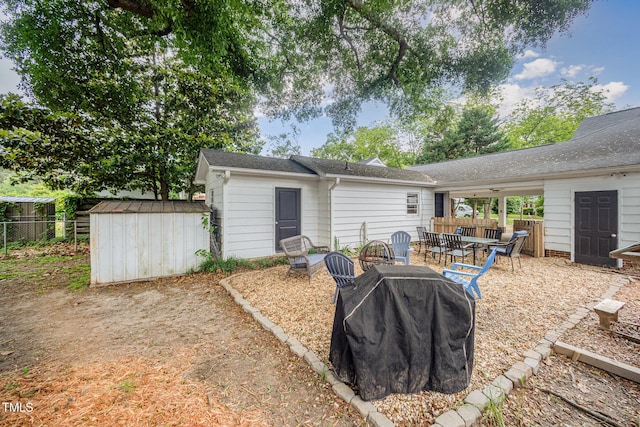 back of house with a storage shed, fence, an outbuilding, and an outdoor fire pit