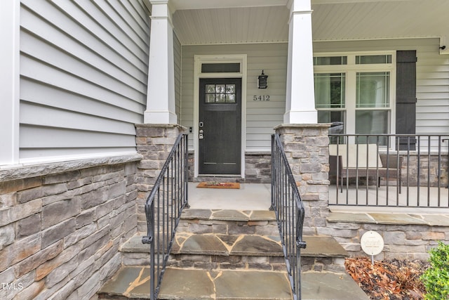 doorway to property featuring a porch and stone siding