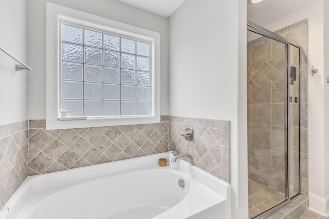 bathroom with plenty of natural light, a stall shower, and a bath