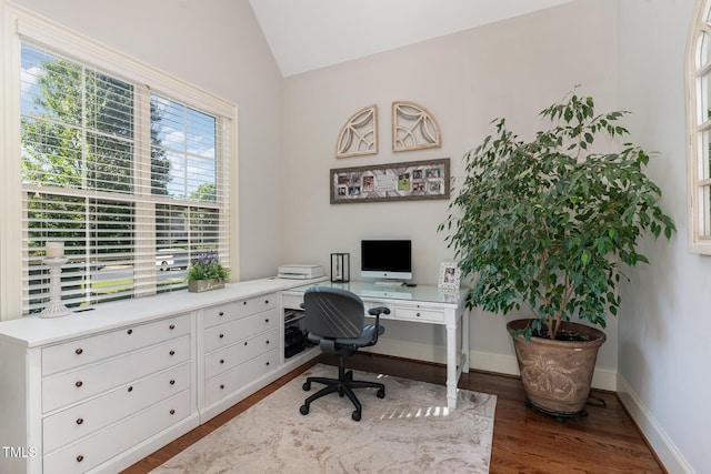 office space with wood finished floors, vaulted ceiling, baseboards, and built in desk