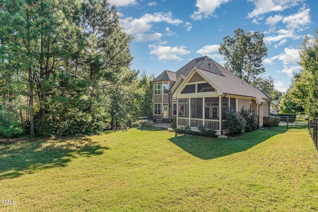 rear view of property with a sunroom, roof with shingles, and a patio