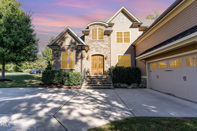 view of front facade featuring stone siding, driveway, and a garage