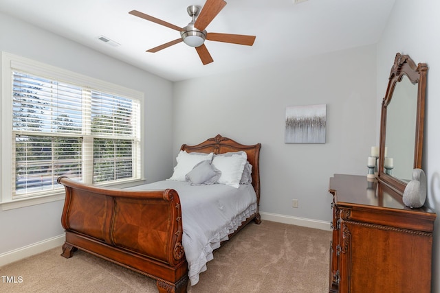bedroom with light colored carpet, baseboards, multiple windows, and a ceiling fan