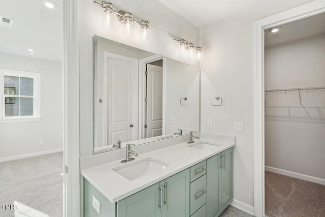 4611 Mint Leaf Ln, Raleigh, NC 27612 - bathroom featuring baseboards, double vanity, a walk in closet, and recessed lighting