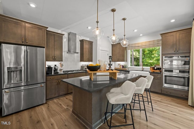4611 Mint Leaf Ln, Raleigh, NC 27612 - kitchen featuring appliances with stainless steel finishes, wall chimney range hood, a center island, recessed lighting, and light wood-type flooring