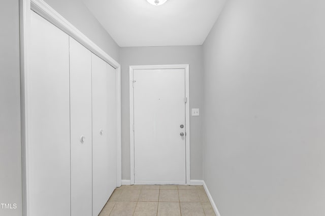 doorway with baseboards and light tile patterned floors