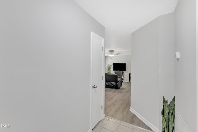 corridor featuring light tile patterned floors and baseboards