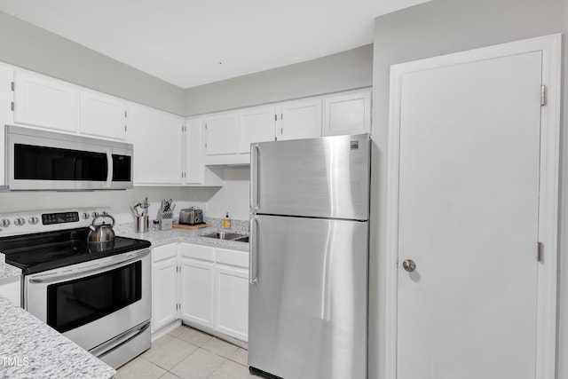 kitchen with stainless steel appliances, light countertops, white cabinets, and light tile patterned floors