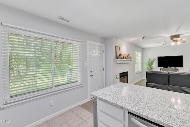kitchen featuring plenty of natural light, a fireplace, ceiling fan, and baseboards