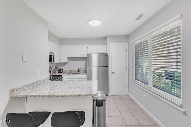 kitchen with appliances with stainless steel finishes, a peninsula, healthy amount of natural light, and a sink