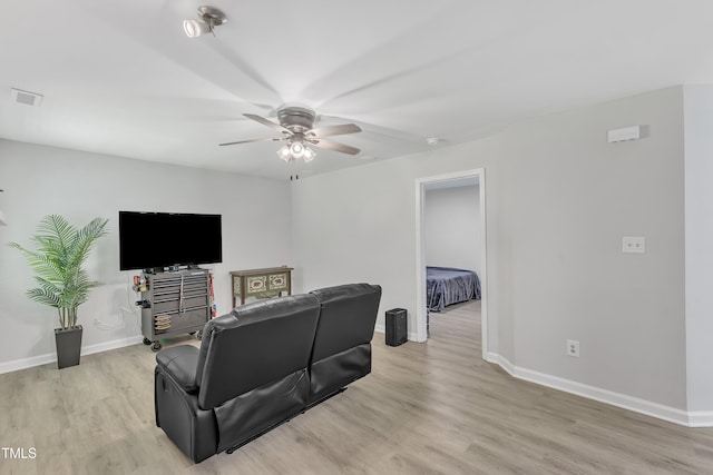 living area featuring ceiling fan, light wood-style floors, and baseboards
