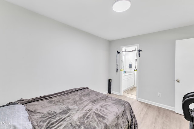 bedroom with light wood-style flooring, baseboards, and connected bathroom