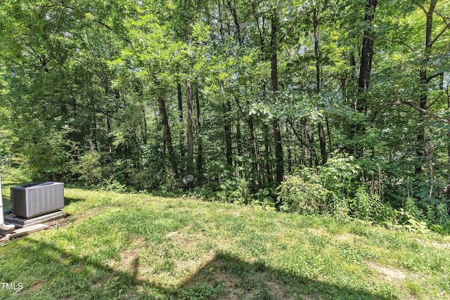 view of yard featuring central AC and a forest view